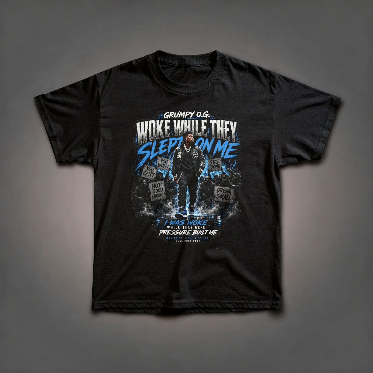 Black Wide Awake™ Tee featuring bold blue and white typography about staying focused while others sleep, with pressure-driven mindset artwork on the front.